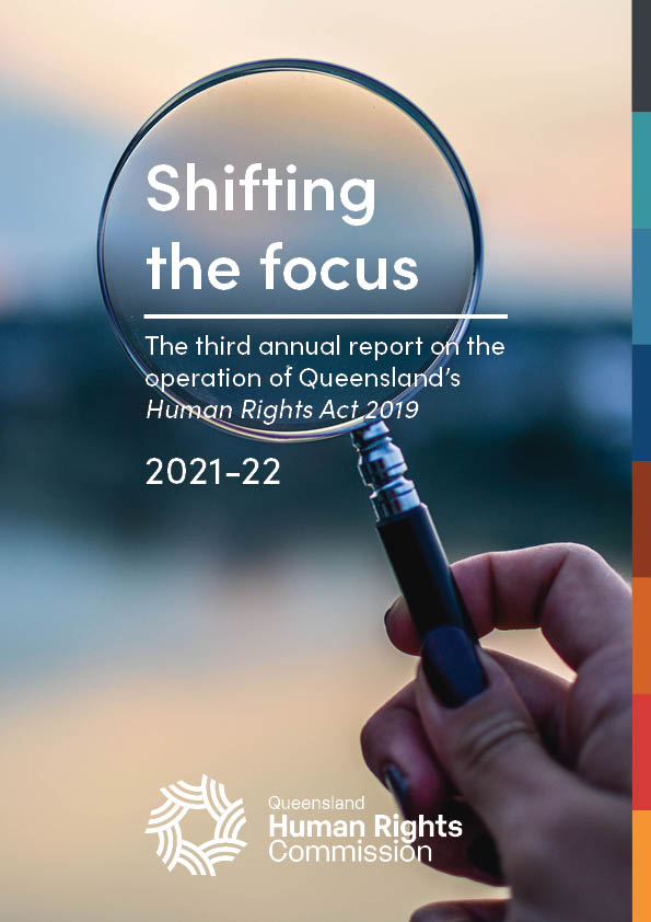Front cover of 'Shifting the focus: The third annual report on the operation of Queensland's Human Rights Act 2019.' Close up of someone holding a magnifying glass up as if to look toward the horizon. The background is out of focus but appears to be outside, maybe at dusk - the colours are muted dark blues and soft peach colours but no shapes or features are discernable. The title of the report is in the centre of the magnifying glass, and the QHRC logo is at the bottom on of the page.