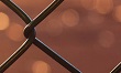 Close up image of chain link fence with orange background